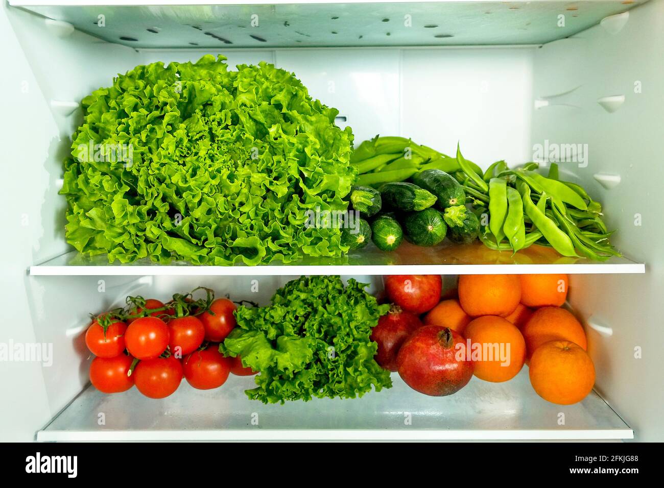 Stacked fridge full of fresh organic fruits and vegetables: orange, carrot, parsley, pepper, cucumber, cauliflower, tomato, lettuce salad, avocado, he Stock Photo