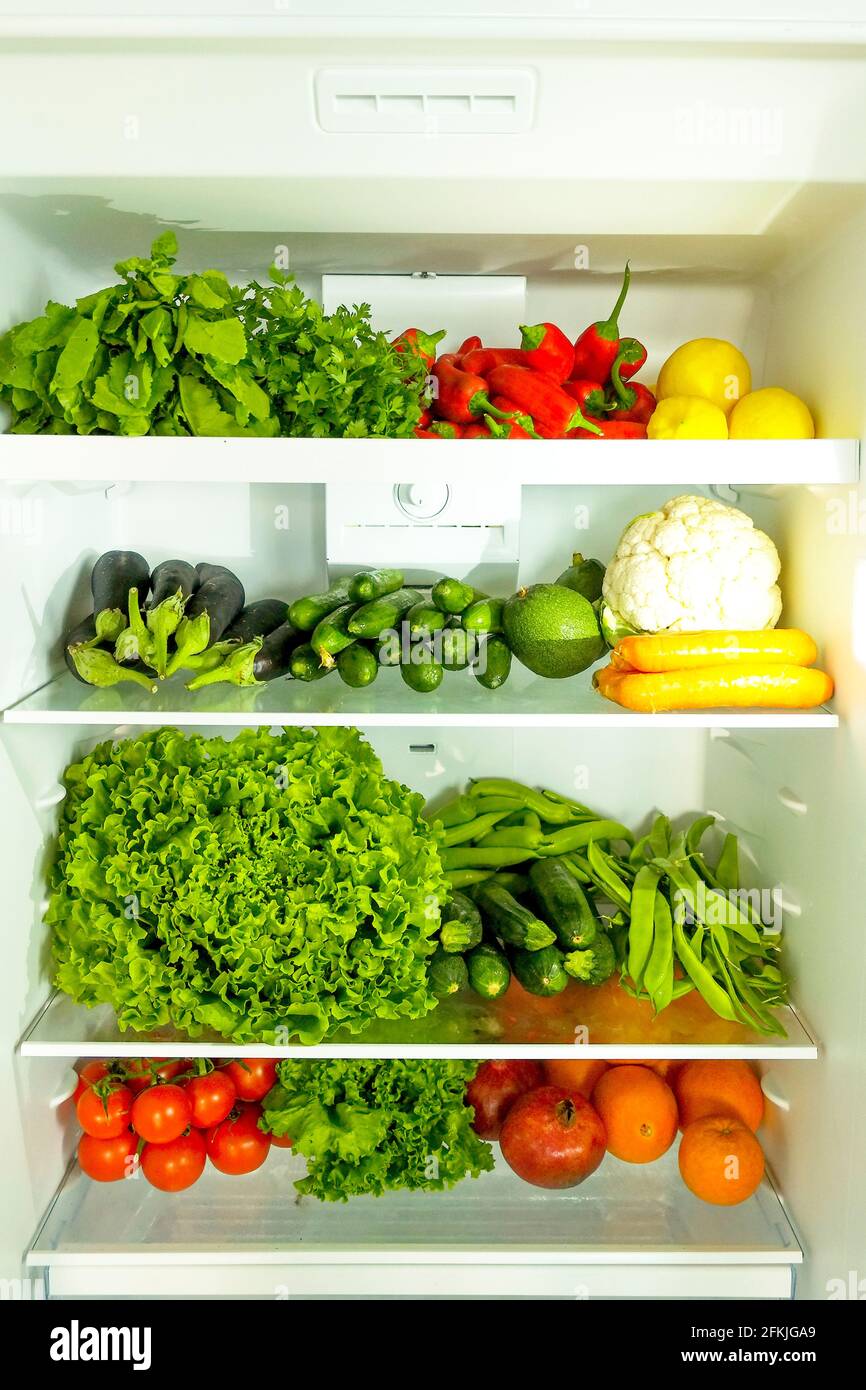 Stacked fridge full of fresh organic fruits and vegetables: orange, lemon, pomegranate, carrot, parsley, pepper, cucumber, cauliflower, tomato, herbs, Stock Photo