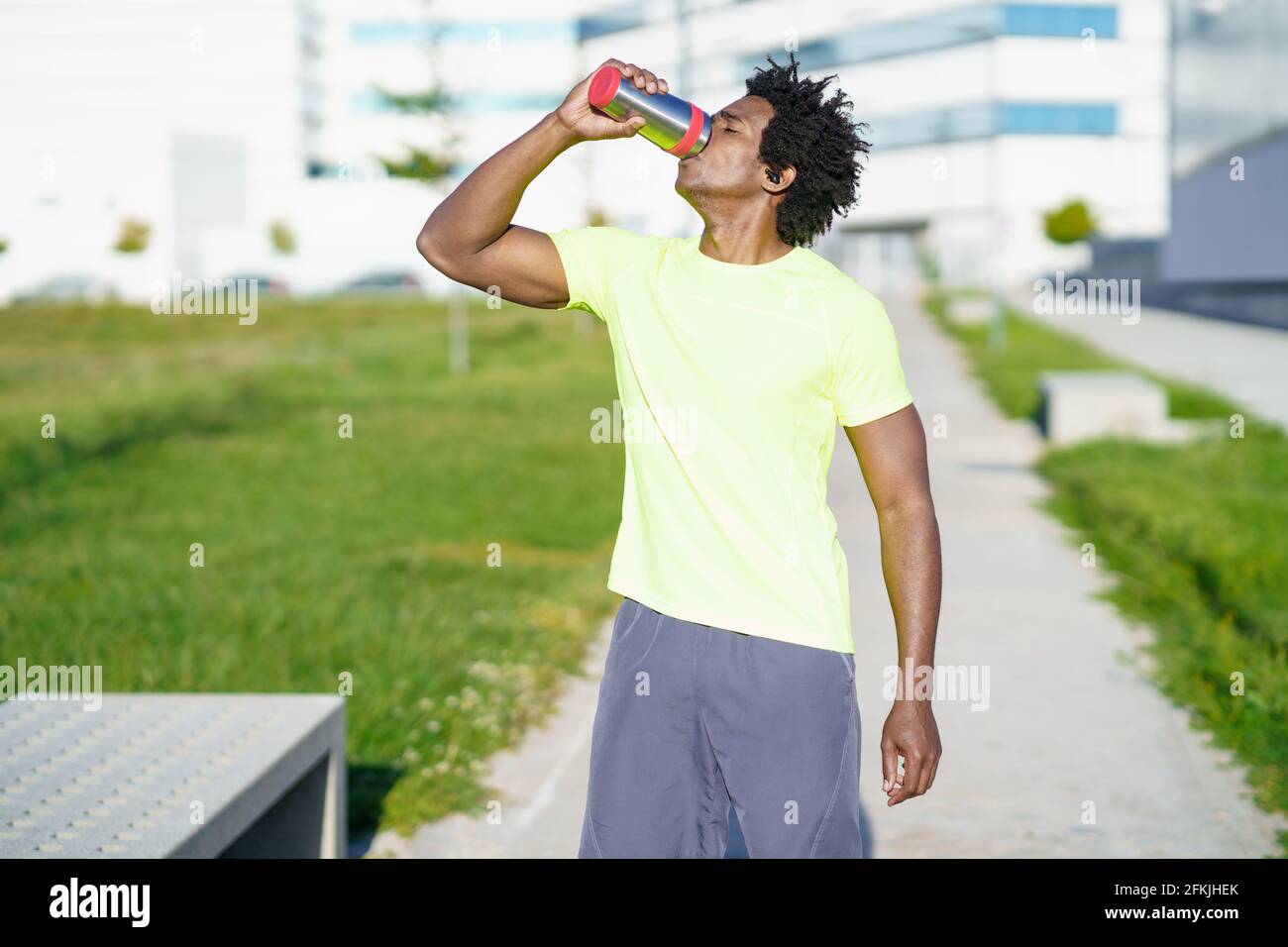Black man drinking during exercise. Runner taking a hydration break. Stock Photo