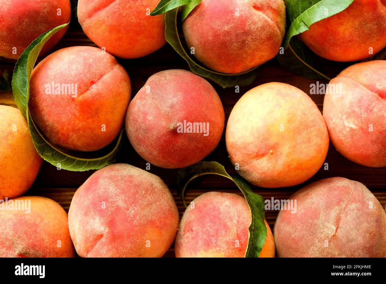 Bunch of ripe freshly picked organic peaches in pile on wooden tray of farmers market. Peach harvest heap. Healthy vegan raw snack. Clean eating conce Stock Photo