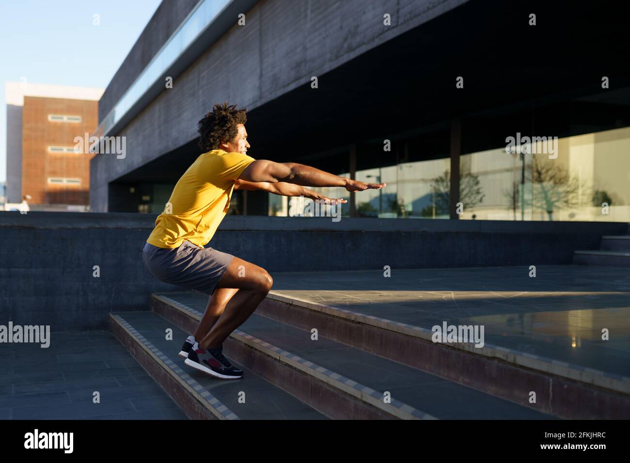 Black man doing squats with jumping on a step. Stock Photo