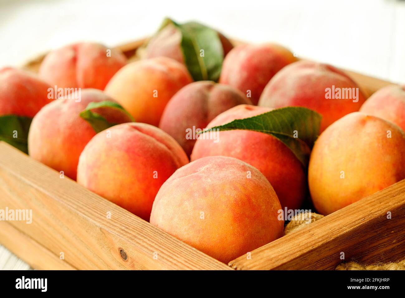 Bunch of ripe freshly picked organic peaches in pile on wooden tray of farmers market. Peach harvest heap. Healthy vegan raw snack. Clean eating conce Stock Photo