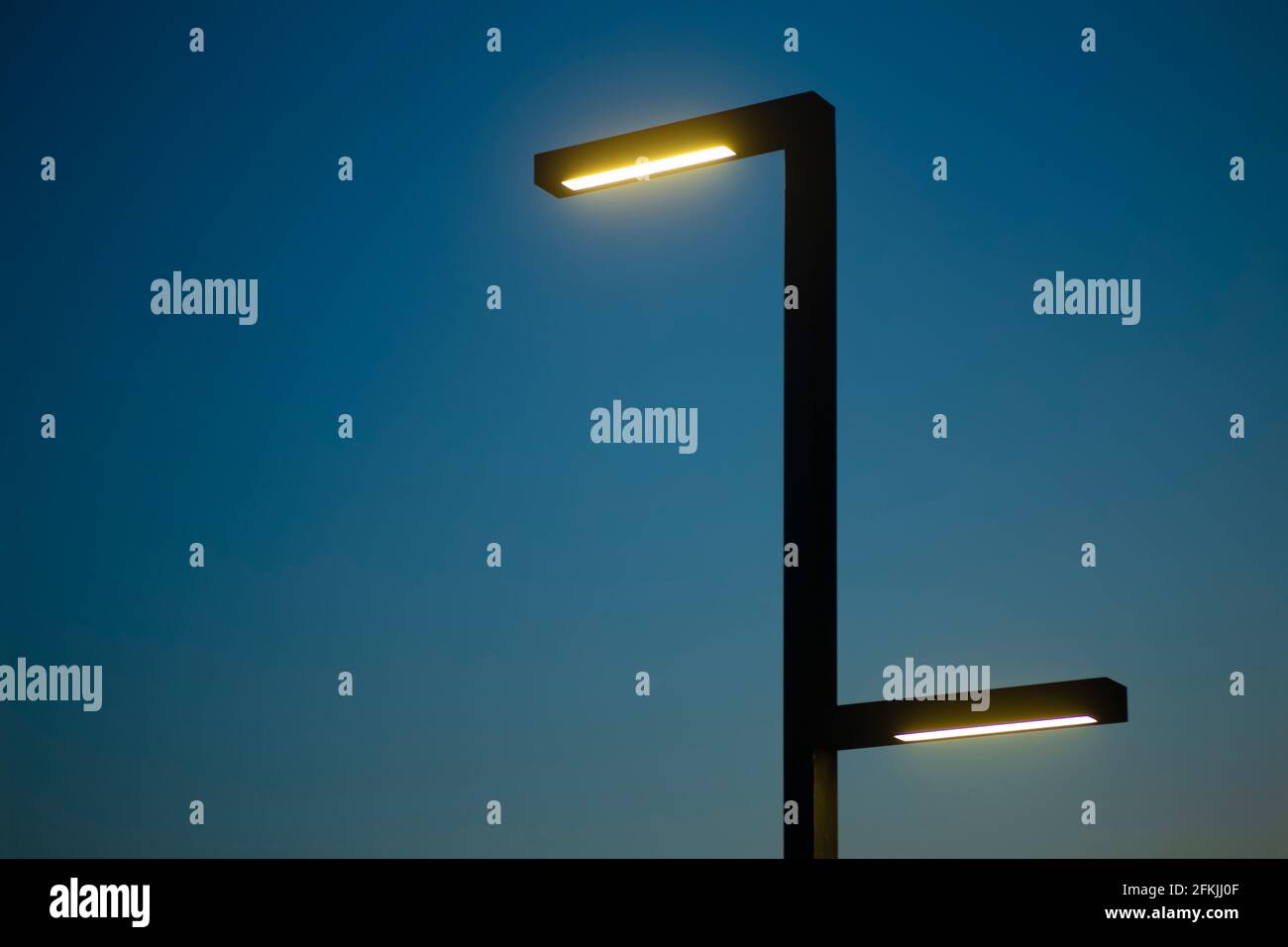 Lamp post against the background of the night sky. Modern lamppost with evening electric lighting. Minimal art photography. Stock Photo