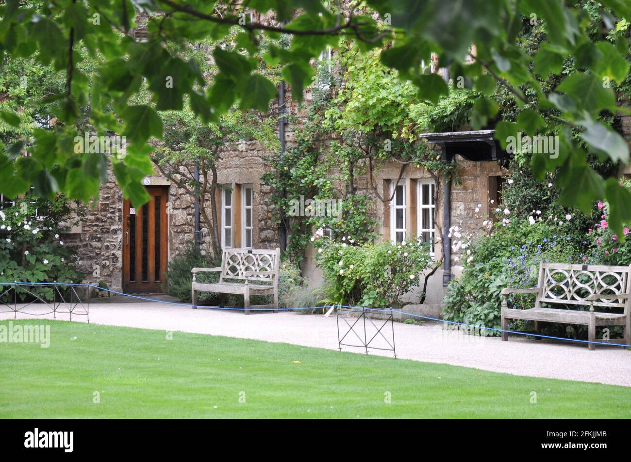 View of lawn and building facade with decorative planting from Hertford College Old Quad, Oxford, United Kingdom. Overcast Sky. Stock Photo