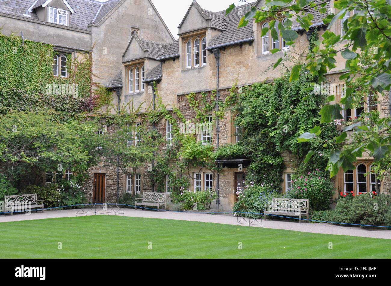 View of lawn and building facade with decorative planting from Hertford College Old Quad, Oxford, United Kingdom. Overcast Sky. Stock Photo