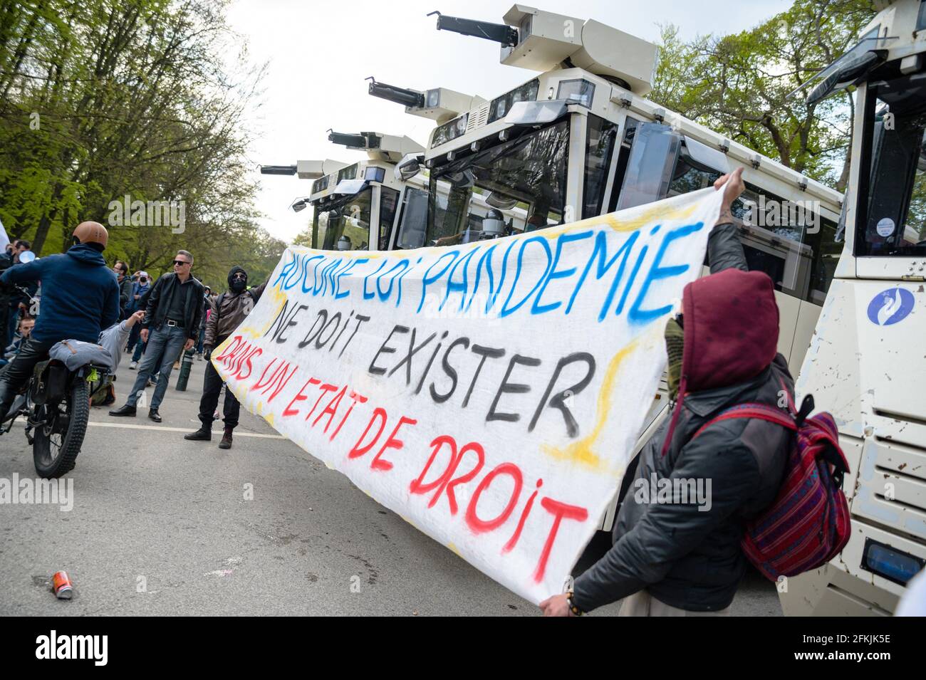 Belgium, Germany, May 1, 2021. People hold a sign reading 'None pandemic law must exist in the rule of law' in front of police cars during Boum 2 event in Brussels, Belgium on May 1, 2021. The Collectif Abime called for a second edition of La Boum, an illegal gathering to protest against the Covid19 mesures and happening in Le Bois de la Cambre in Brussels. Photo by Julie Sebadelha/ABACAPRESS.COM Stock Photo