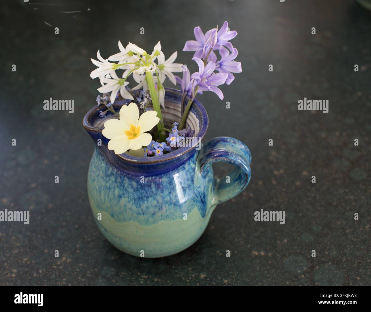 Blue ceramic jug with a posy of spring flowers Stock Photo