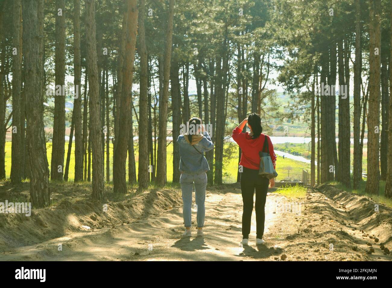 Two Young women resting after walk in the forest, carrying a backpack ...