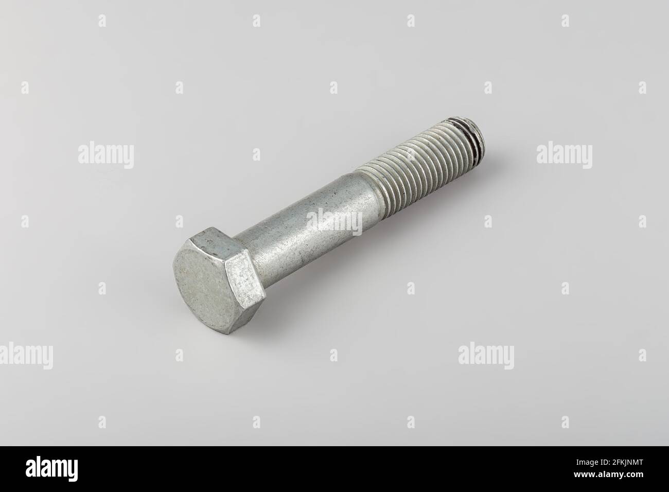 Bolt fastening of the tie spring on a gray background. Truck spare parts mounting bolt. Transmission mounting bolt. Stock Photo