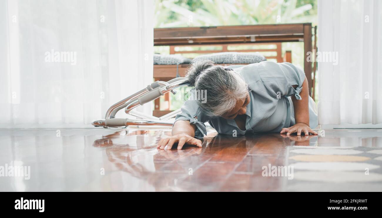 Asian senior woman falling down on lying floor at home after Stumbled at the doorstep and Crying in pain and asking someone for help. Concept of old e Stock Photo