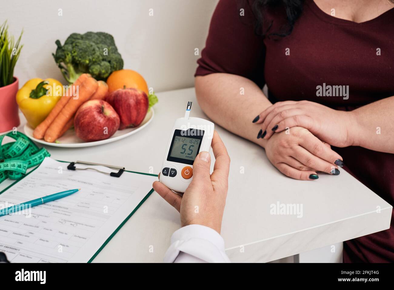 Measuring blood sugar. Nutritionist using glucometer tests overweight woman's blood sugar, prevention control of diabetes Stock Photo