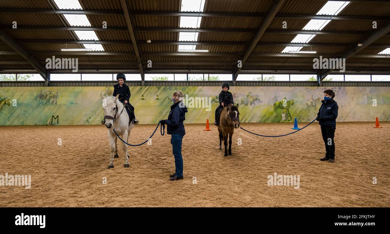 Boys on horses in therapeutic session in riding arena at Riding for disabled, Muirfield Riding Therapy, East Lothian, Scotland, UK Stock Photo