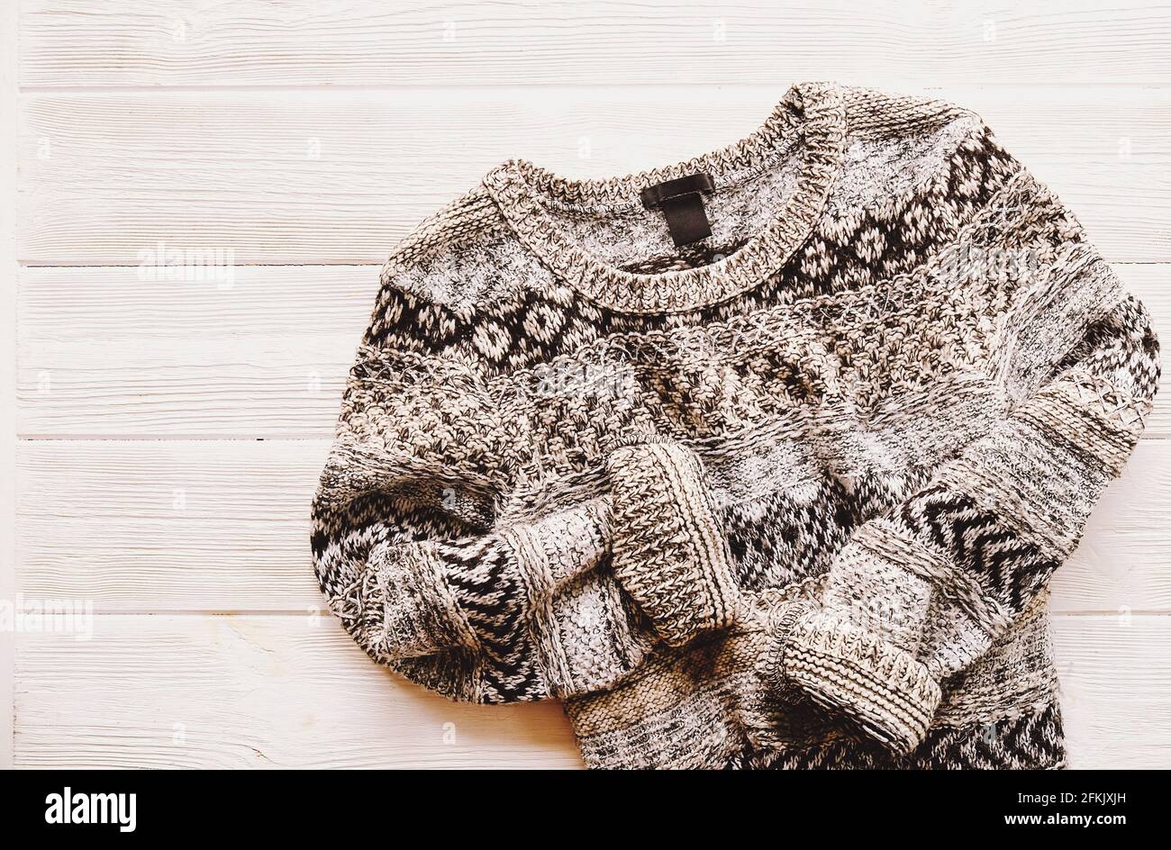 Fashionable easy chic casual style oversized sweater with buttons on white wood textured table background. Top view, close up, copy space. Stylish wom Stock Photo