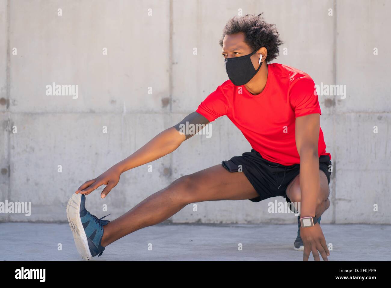 Afro athletic man stretching legs before exercise. Stock Photo