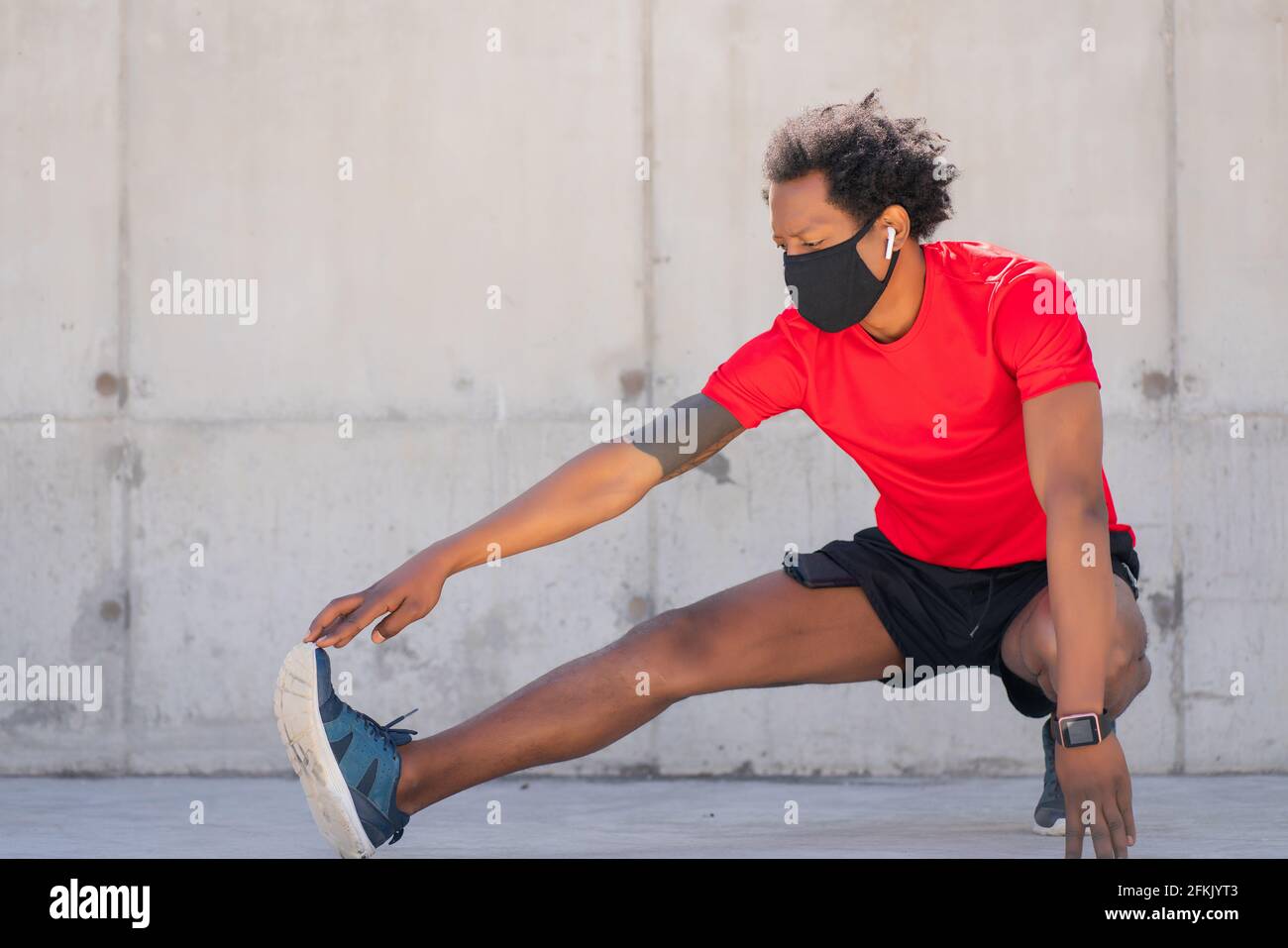 Afro athletic man stretching legs before exercise. Stock Photo