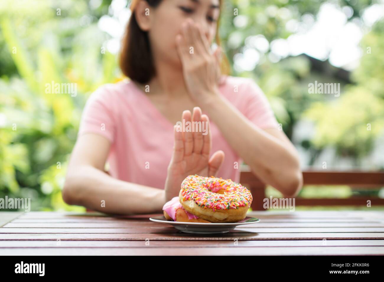 The beautiful Asian healthy middle aged woman sitting on the balcony beside the garden and Refuse to eat the nut. Concept of health care and nutritiou Stock Photo
