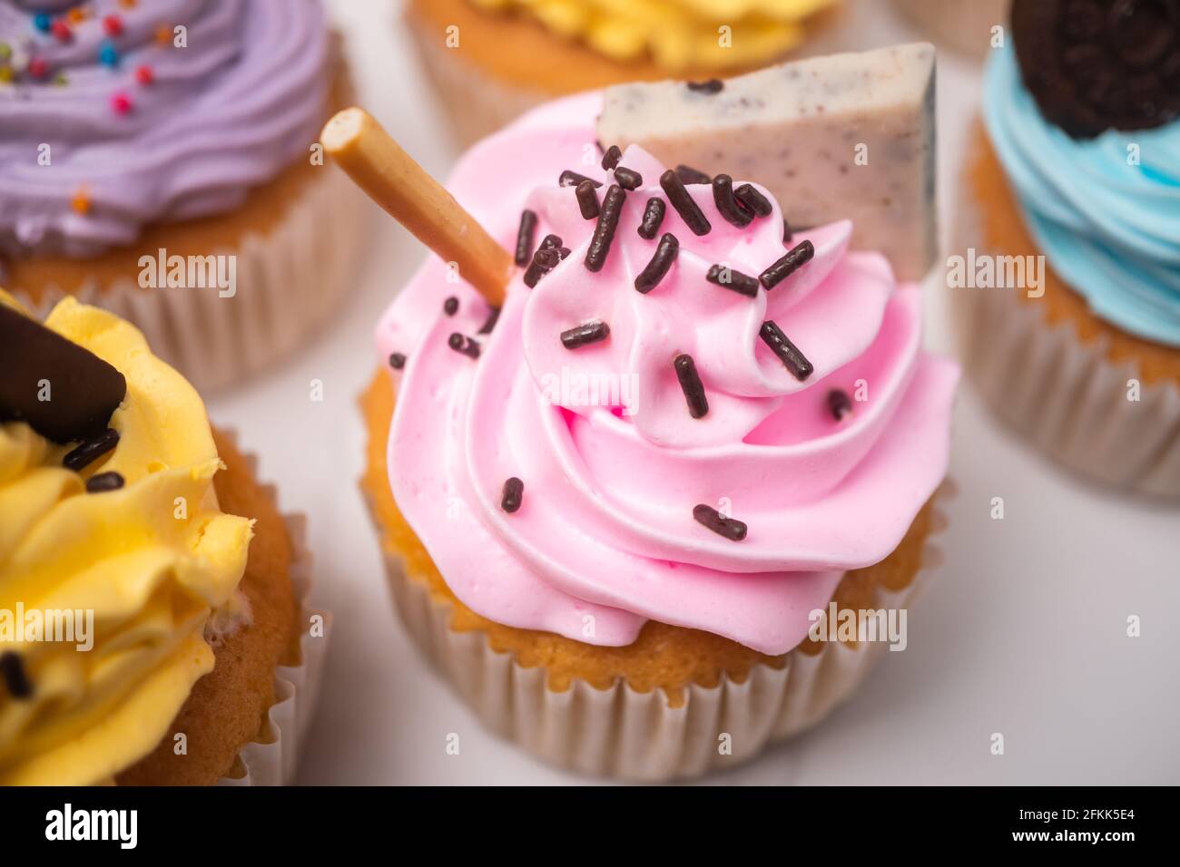 Delicious homemade cupcakes with Colorful cream and topping with candy and Chocolate Cookies. Homemade autumn holiday dessert Stock Photo