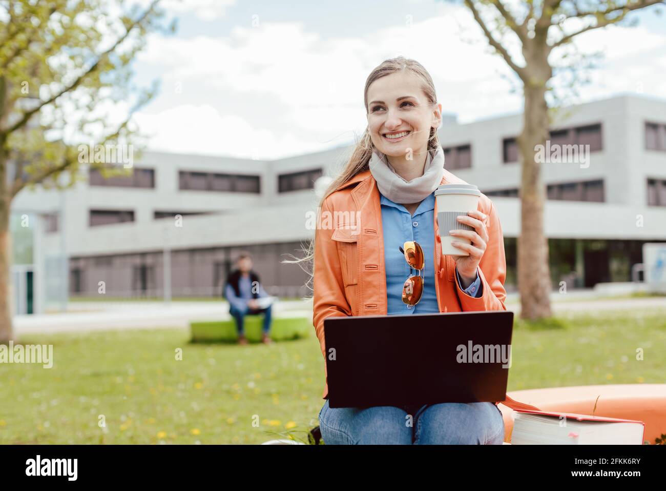 Student with coffee and laptop in front of university building Stock Photo