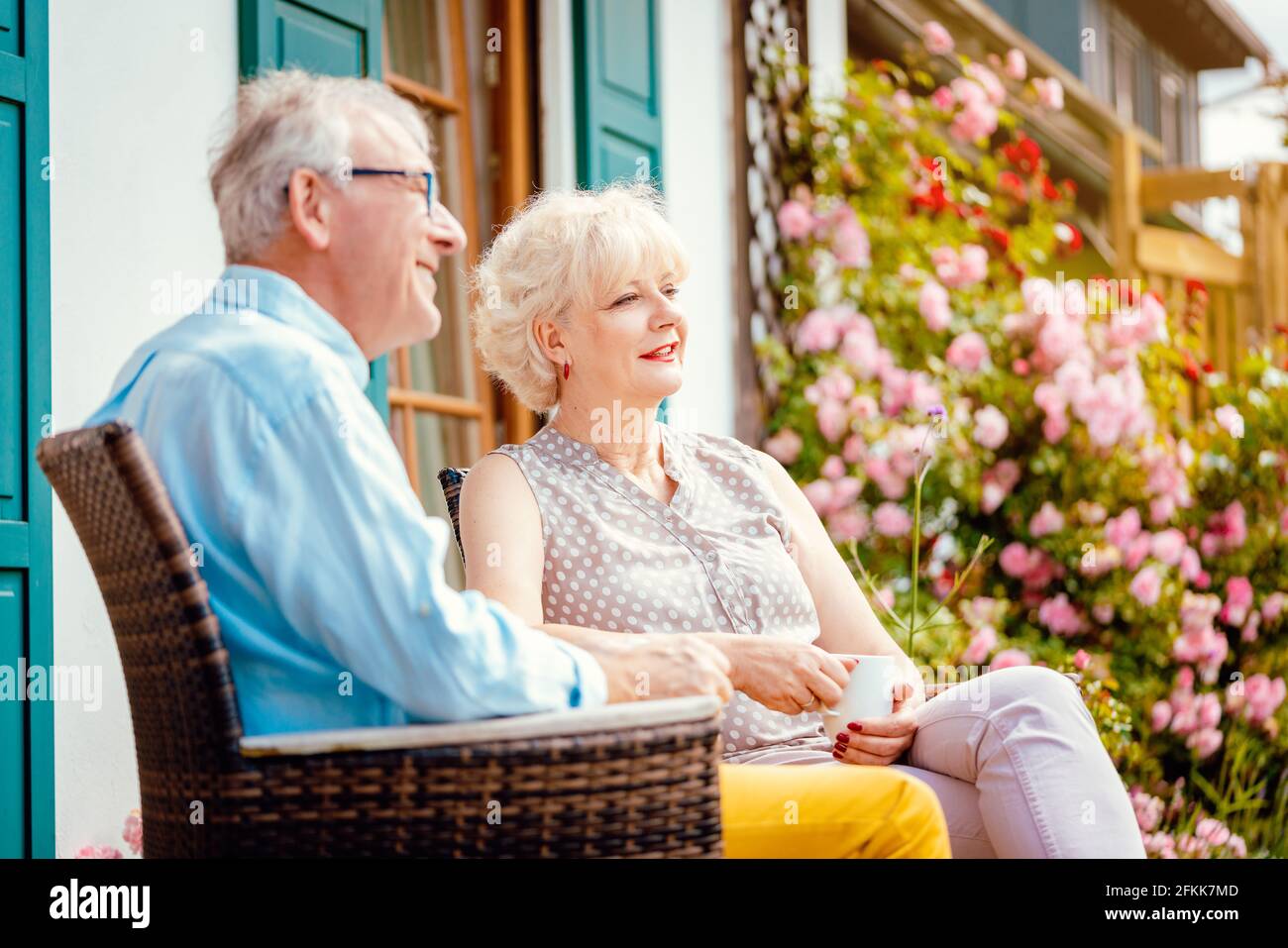 Senior couple enjoying their coffee on porch in front of their house Stock Photo