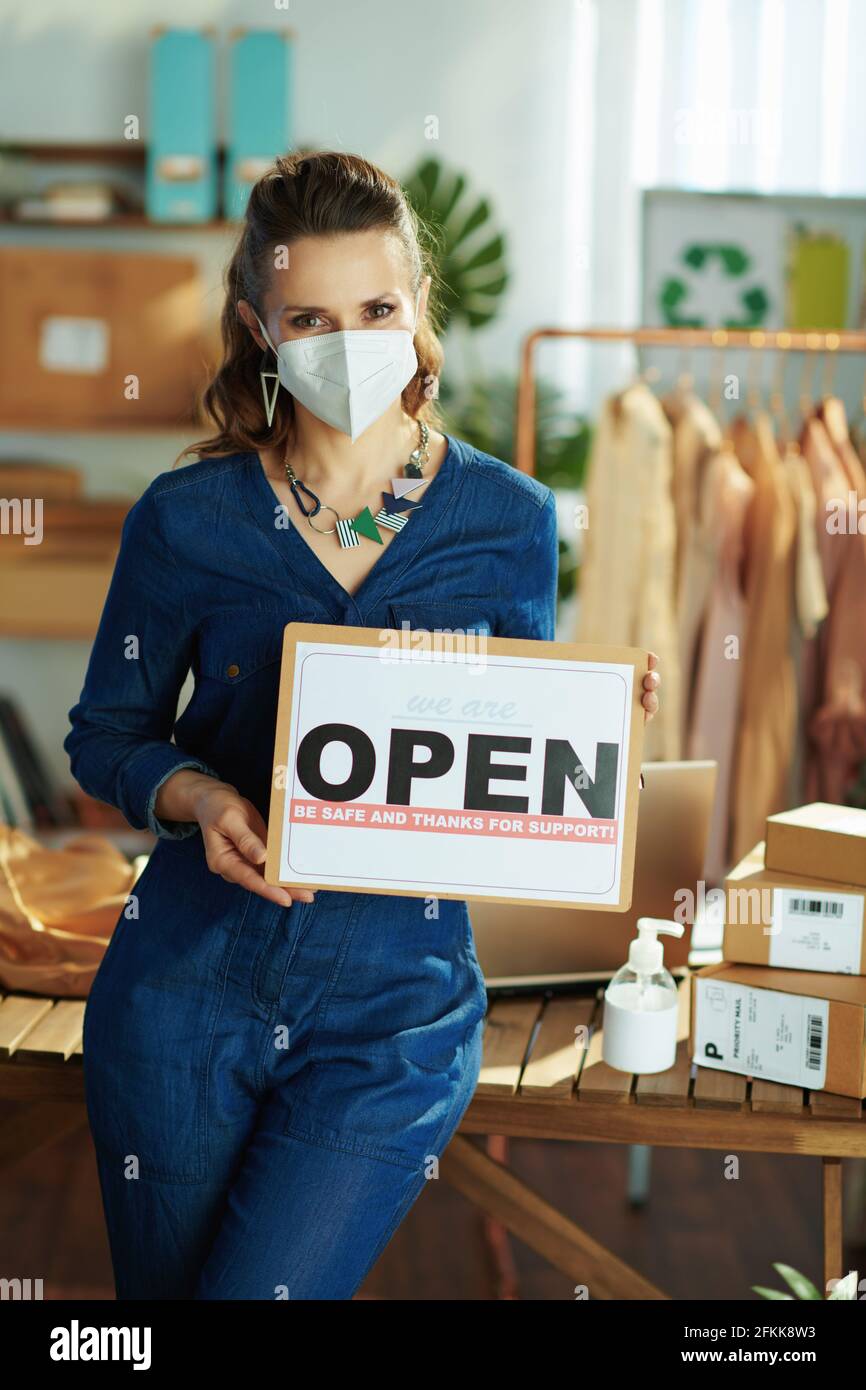 modern small business owner woman with ffp2 mask, open after covid sign and antiseptic in the office. Stock Photo