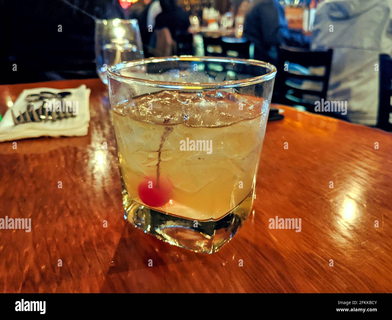 whiskey sour drink in a cocktail glass with ice on a wood table in a restaurant bar Stock Photo