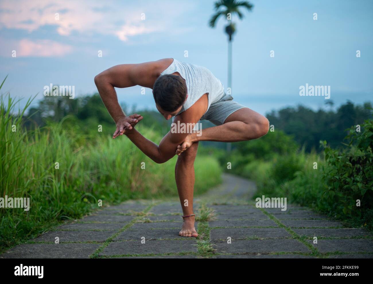 Young fit male practicing yoga and doing the balancing stick pose outdoors  Stock Photo - Alamy