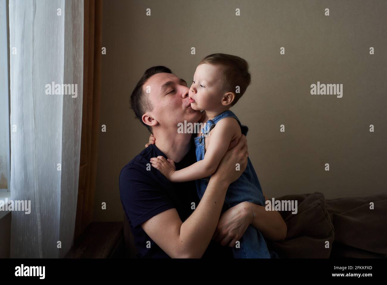 Father holding in arms his little son and kissing him outdoor. Happy family and father care concept. Stock Photo