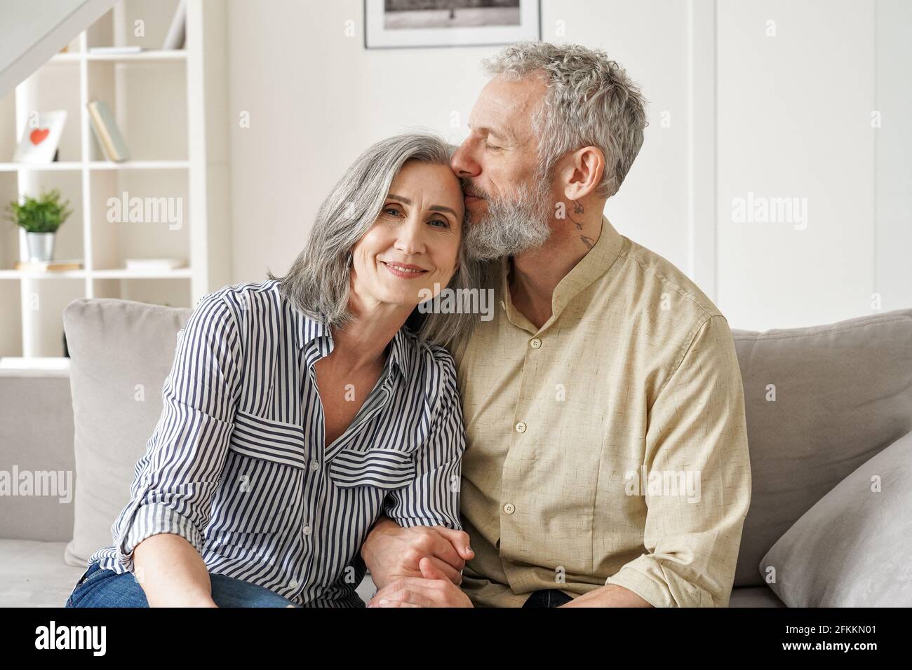 Happy affectionate classy older mature couple bonding with eyes closed at home. Stock Photo