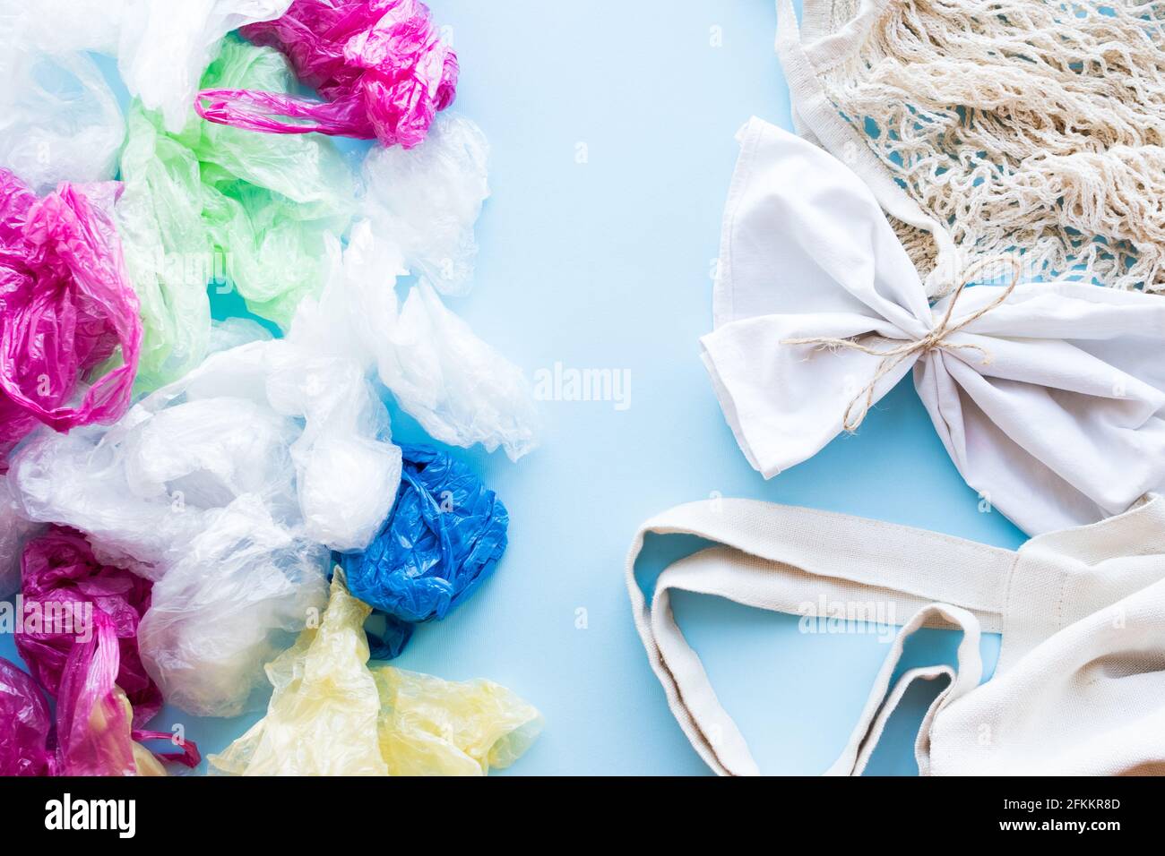 Many disposable plastic bags vs reusable cotton bags on a blue