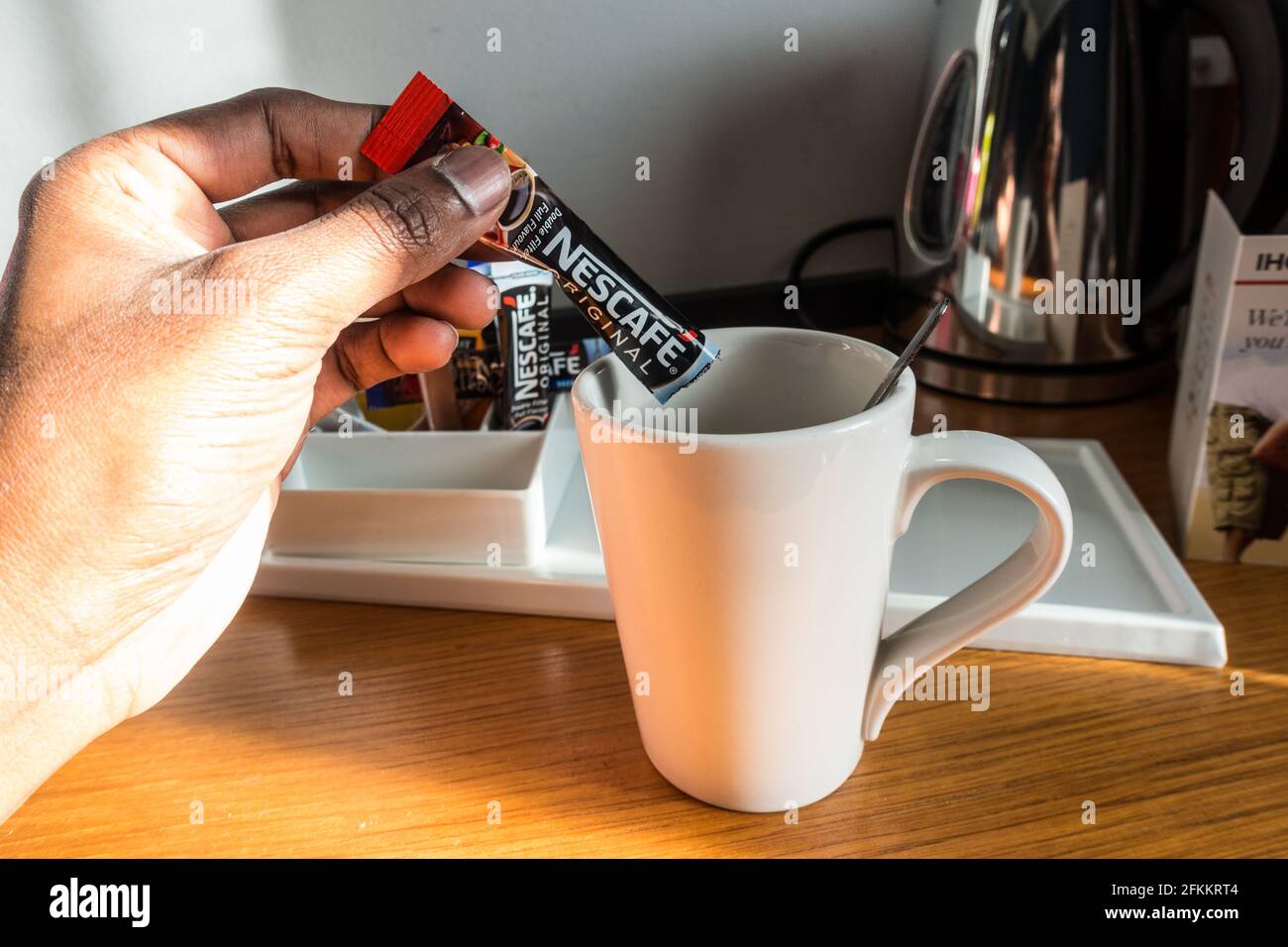 Adult Asian male hand pouring coffee powder from sachet into cup at a hotel room Stock Photo