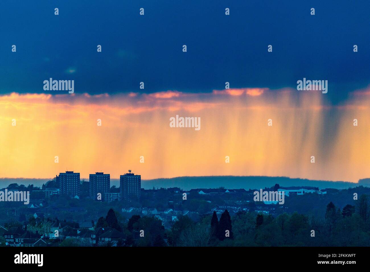 Brierley Hill, West Midlands, UK. 2nd May, 2021. An orange sky and heavy showers fall over blocks of flats in Brierley Hill in the Black Country, West Midlands, as the sun sets. Bank Holiday Monday's weather forecast is heavy rain and strong winds across the country. Peter Lopeman/Alamy Live News Stock Photo