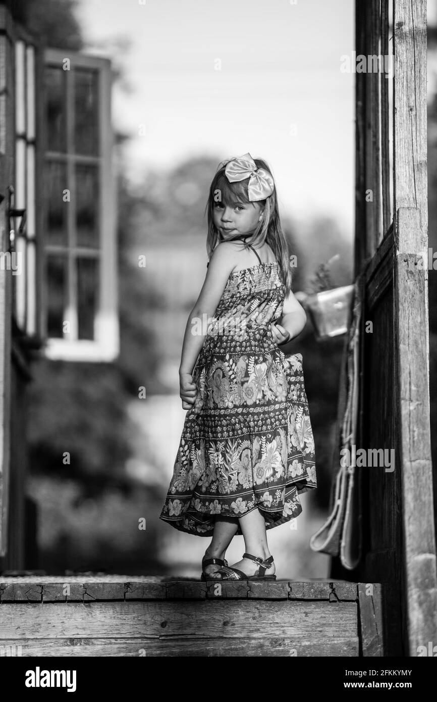 Little five-year girl posing for the camera on the porch of a village ...