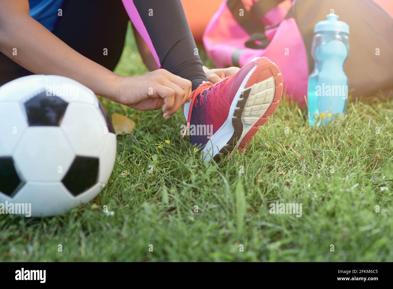 Little girl football player tying shoelaces outdoors Stock Photo Alamy