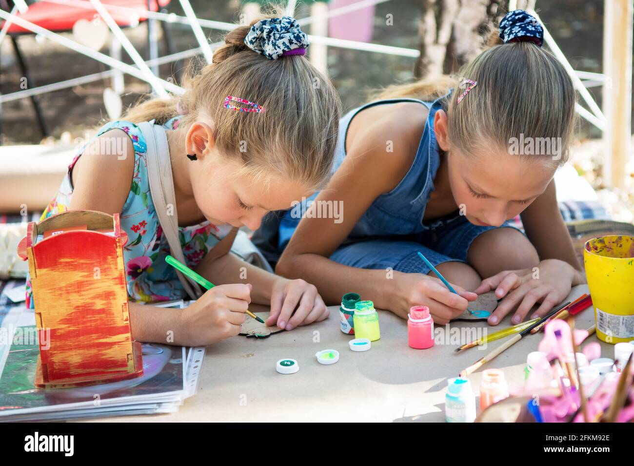 two girls diligently paint with brushes and paints on the boards Stock Photo