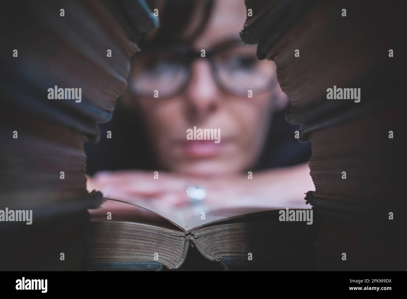 A woman with many books reads comfortably in her library Stock Photo