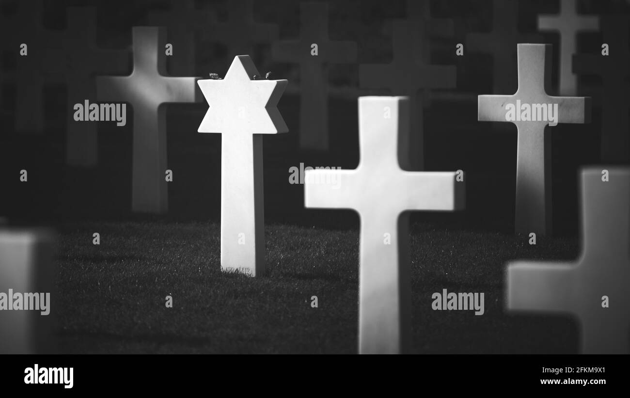 A monochrome shot of a dark cemetery with white cross and star gravestones Stock Photo