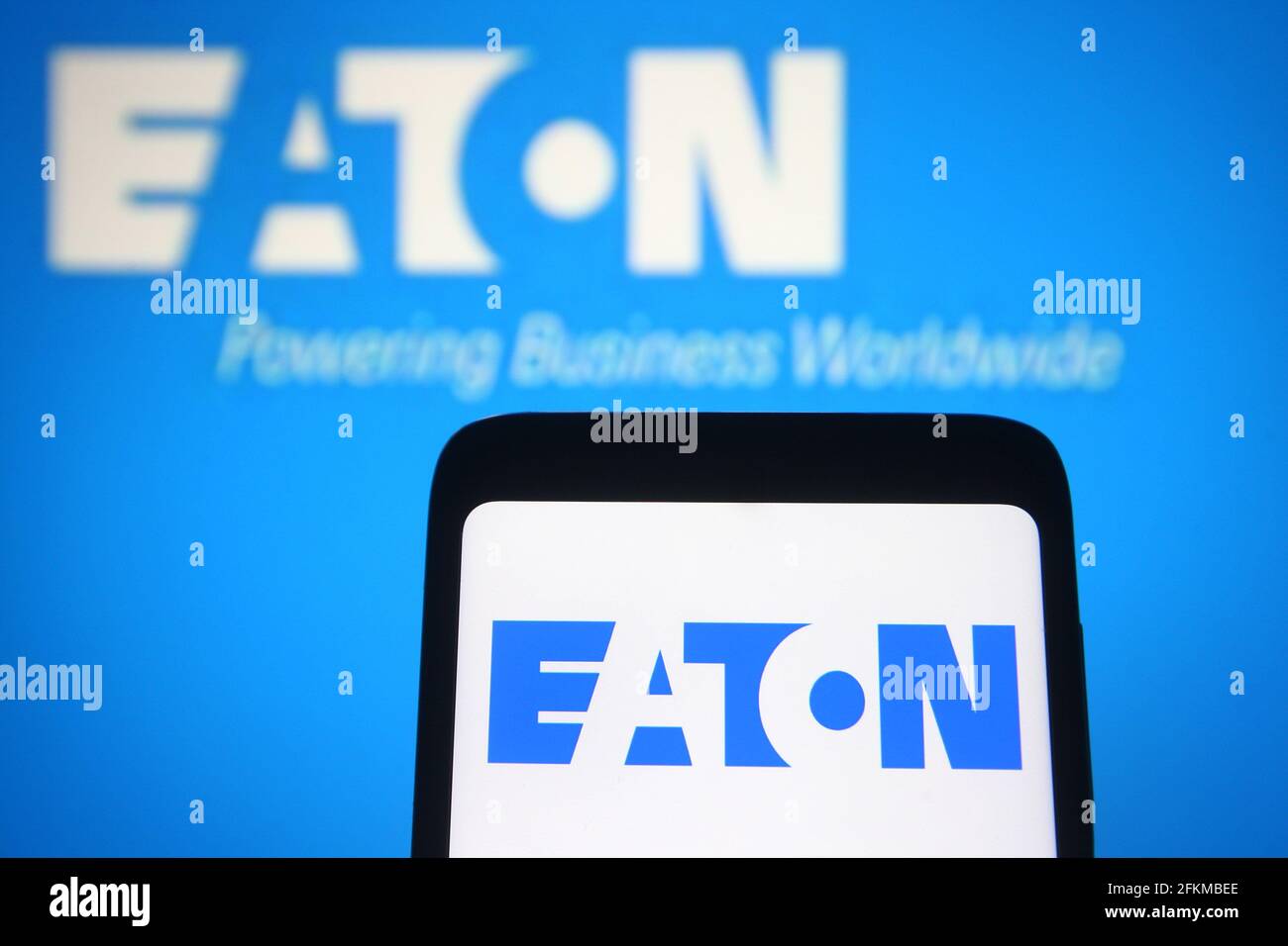 In this photo illustration an Eaton corporation logo is seen on a smartphone and a pc screen. Stock Photo