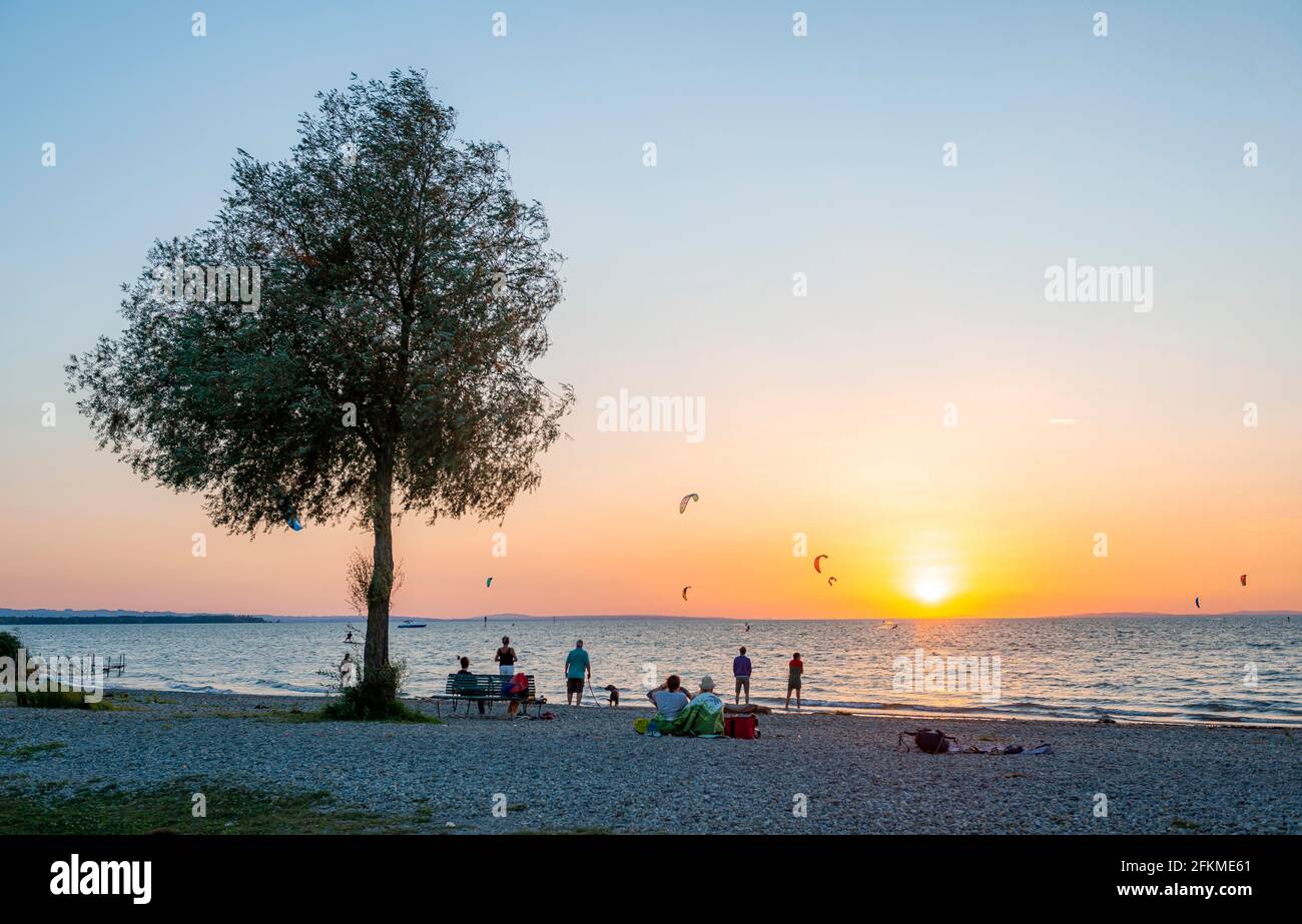People on the shore of Lake Constance, kitesurfers in the lake, sunset, Bavaria, Germany Stock Photo