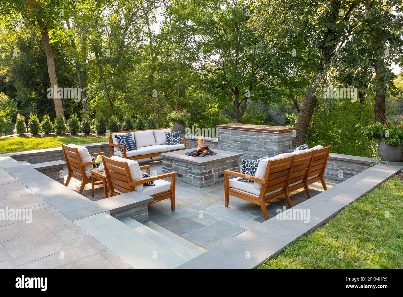 Sunken bluestone firepit and television area in garden with teak furniture Stock Photo