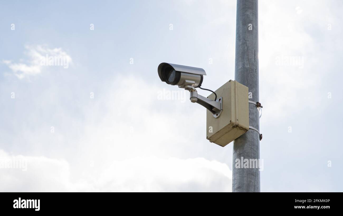 Surveillance camera mounted on a pole with sky background Stock Photo