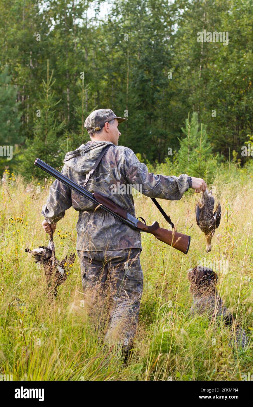 the hunter holds in his hands a hunting prey - two downed black grouses Stock Photo