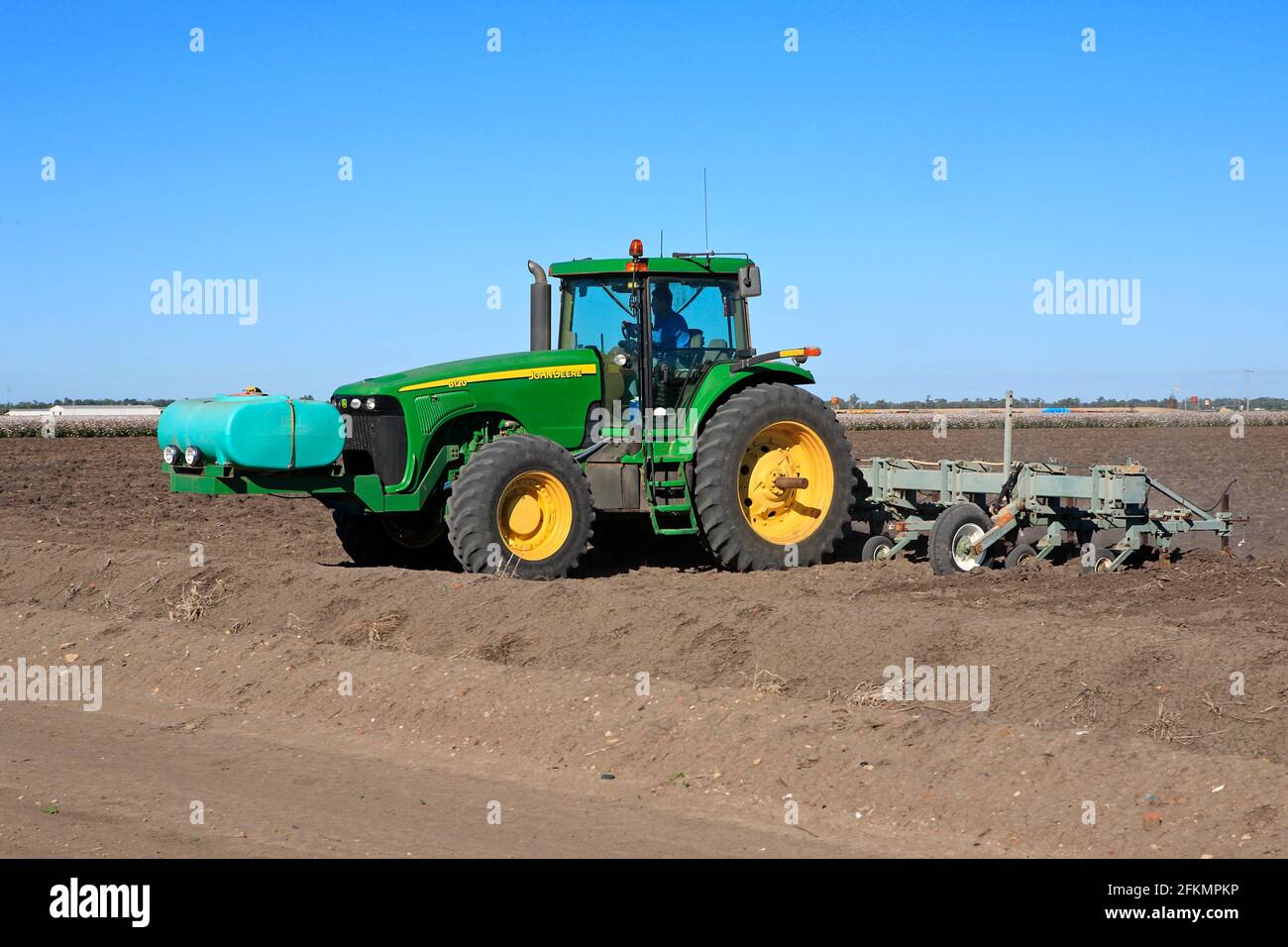 John Deere 8120 tractor plowing a cotton field near Narrabri, NSW, Australia. There is a liquid fertiliser tank on the front of the tractor. Stock Photo
