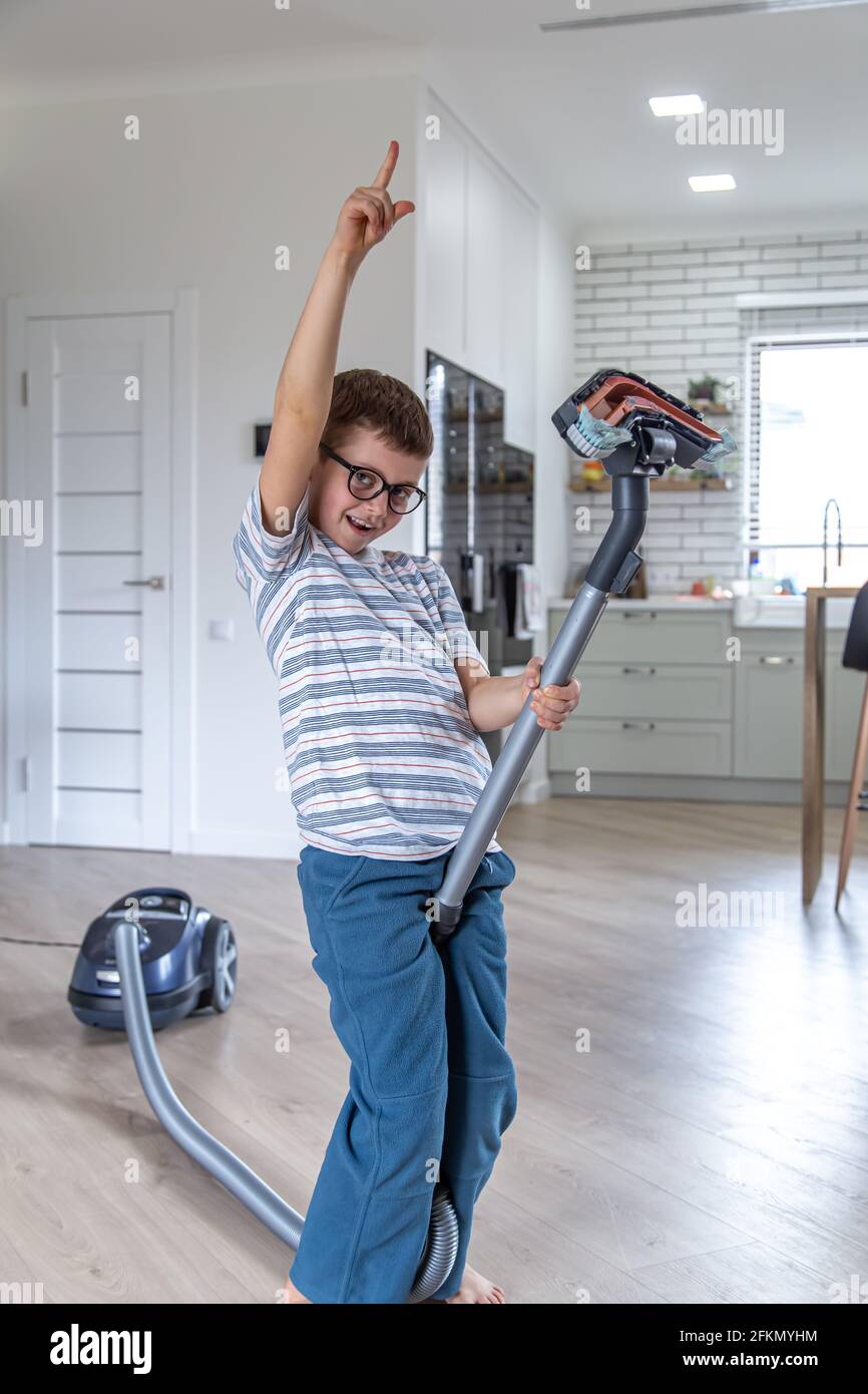 A little boy with glasses is having fun and cleaning the house with a ...