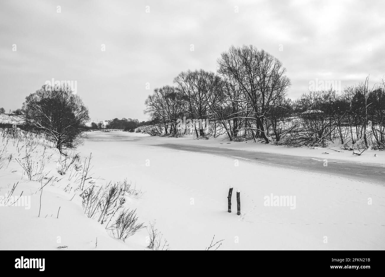 Black and white rural winter or springtime landscape with frozen river Stock Photo