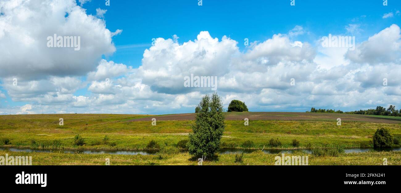 Summer sunny rural landscape with small river and farm fields Stock Photo