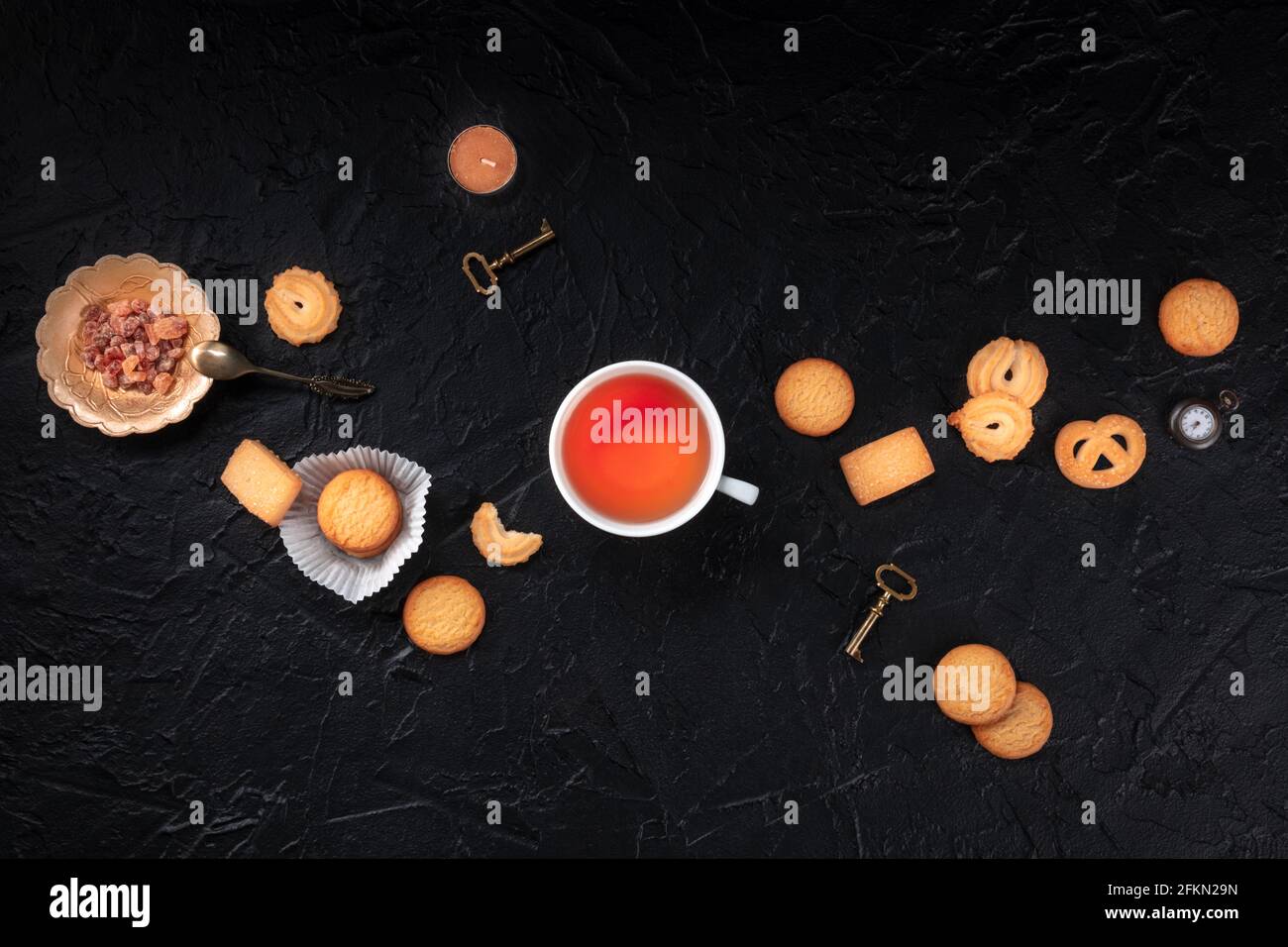 Danish butter cookies, a still life with tea and keys, top shot on a black background, a flat lay composition Stock Photo