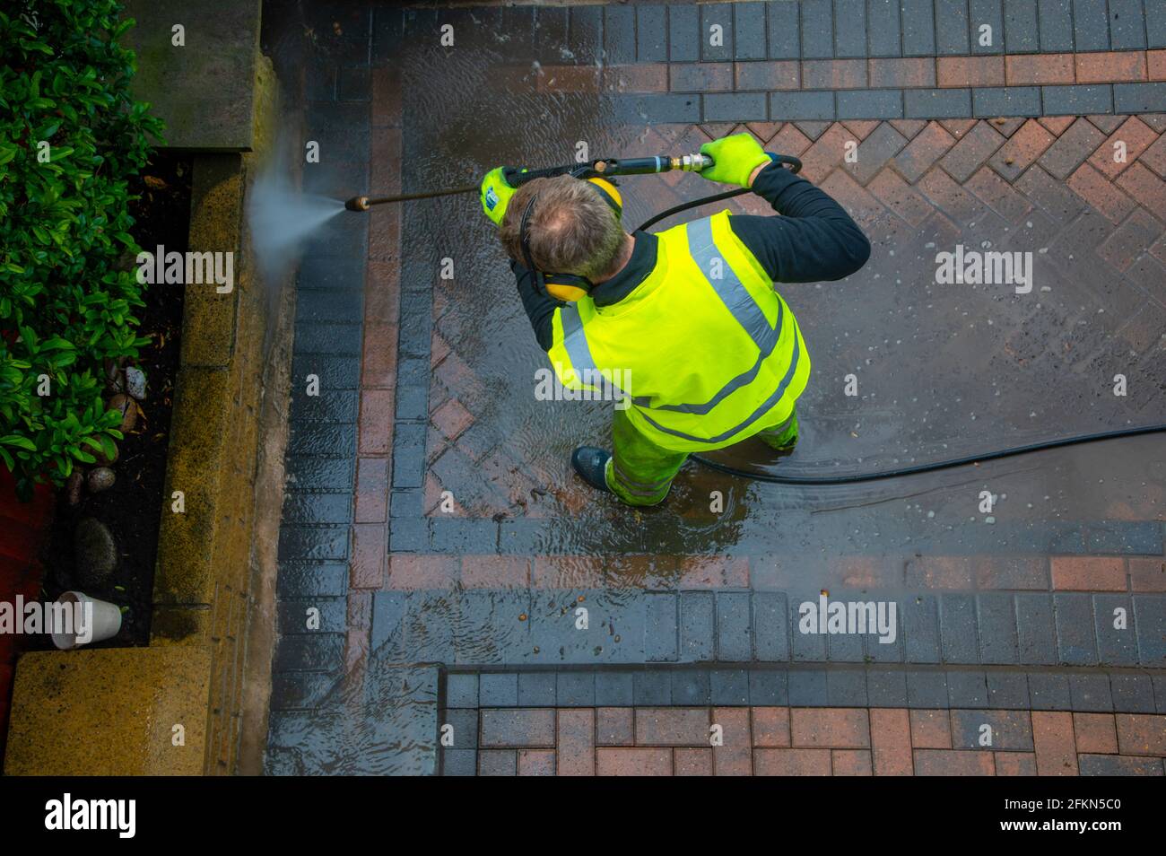 Contractors cleaning domestic block paved driveway with high pressure water Stock Photo