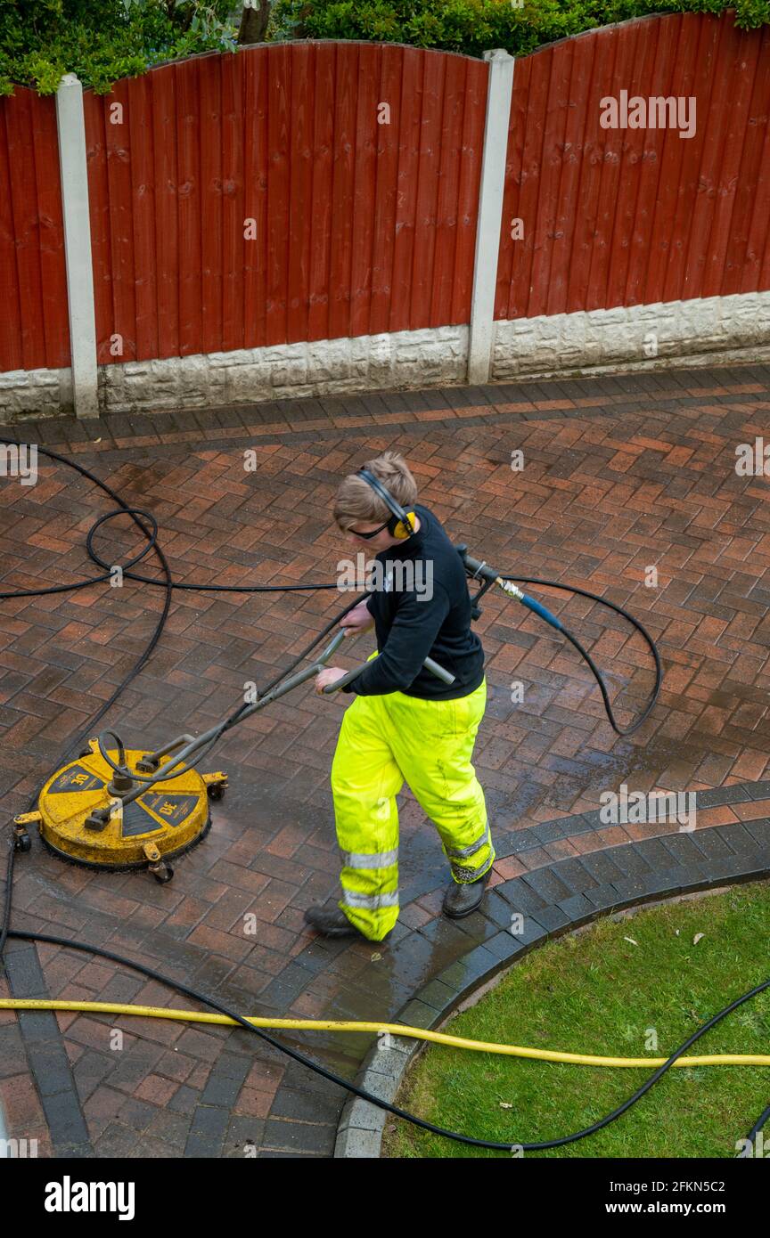Contractors cleaning domestic block paved driveway with high pressure water Stock Photo