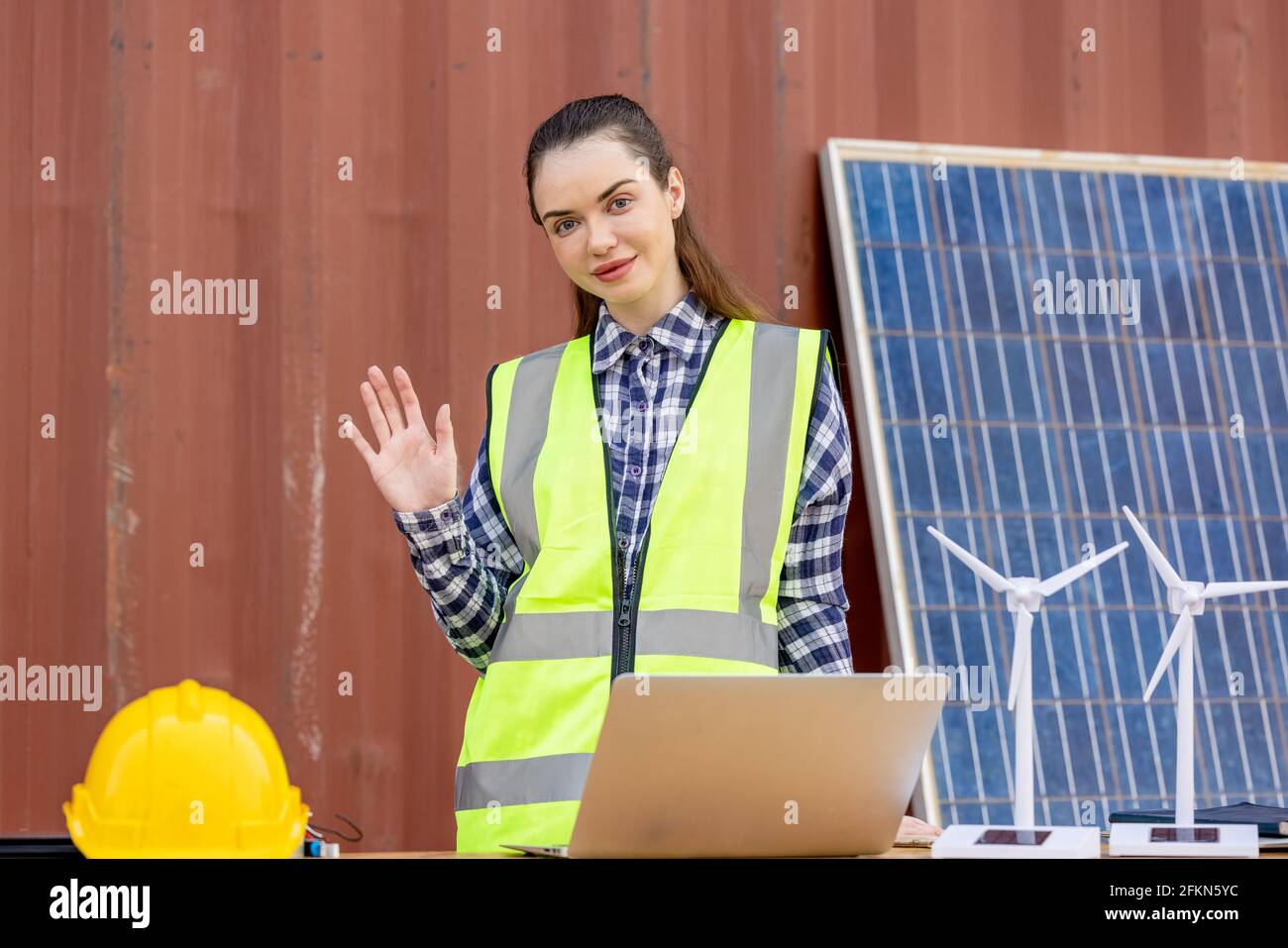 factory workers or engineers holding light bulb and using tablet computer with windmill model on solar panel,  work in containers warehouse storage Stock Photo
