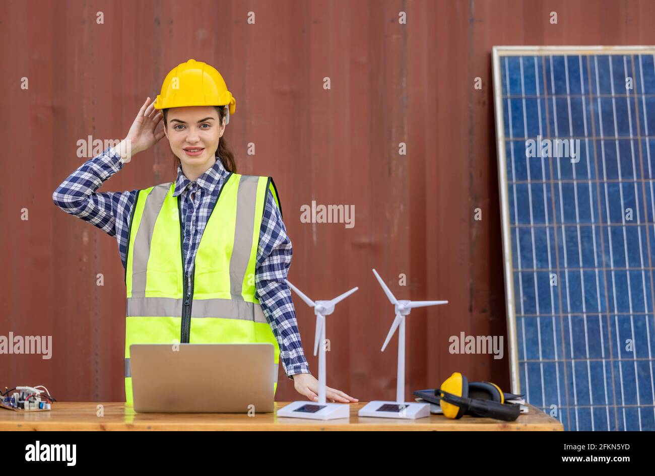 factory workers or engineers holding light bulb and using tablet computer with windmill model on solar panel,  work in containers warehouse storage Stock Photo